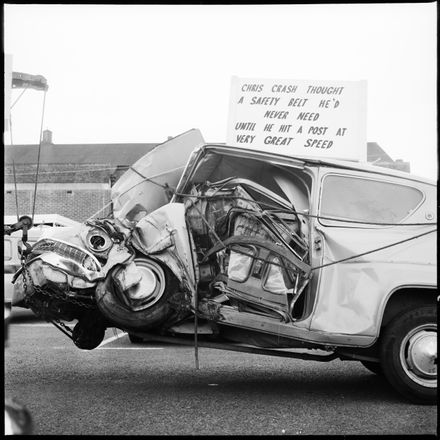 [A wrecked car with a sign encouraging seat belt wearing, being towed in the road safety parade.]