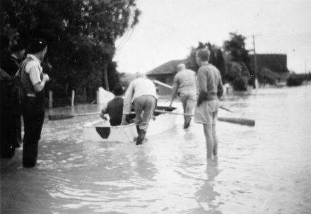 People and boat on flooded road