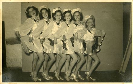Six dancers dressed in white satin dresses