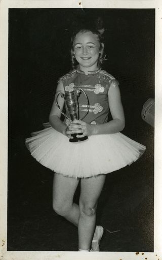 Karen or Leanne Archer dressed in a tutu, holding a trophy