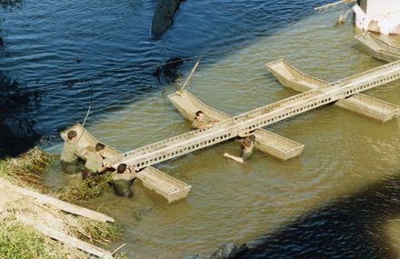 Army personnel assembling a bailey bridge
