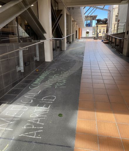 Chalked protest slogans outside Palmerston North City Library