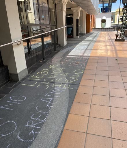 Chalked protest slogans outside Palmerston North City Library