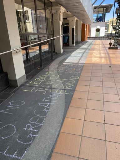 Chalked protest slogans outside Palmerston North City Library