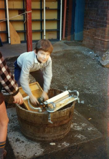 School pupil washing clothes by hand at the museum in Palmerston North