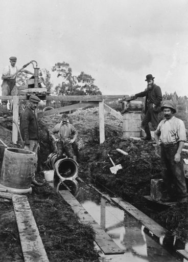 Workmen laying sewer pipes