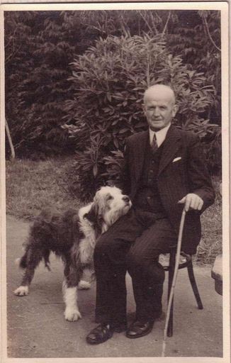 Mr Gimblett sitting in chair in garden with long-haired dog