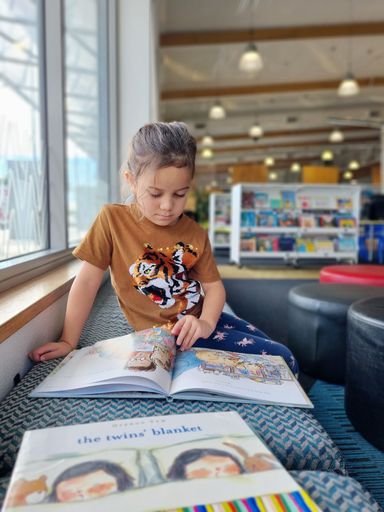 Lyra reading in the Children's section - Resource cover image