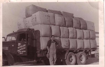 Wilf Lincoln standing beside truck loaded with bales of wool, 1951