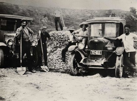 Men (unidentified) loading 2 trucks with unknown material