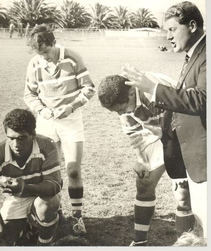 Coach talking to rugby team members during 1/2 time