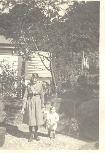 Woman and child in garden in front of water tank.