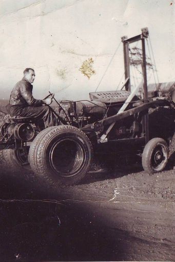 Man (Stan Graham ?) on tractor with bucket scoop operated by cables