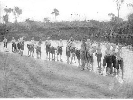 Boys standing at edge of river