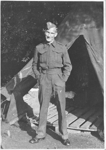 A soldier, probably Jack Kingsbury, standing outside a tent with a wooden pallet floor.
