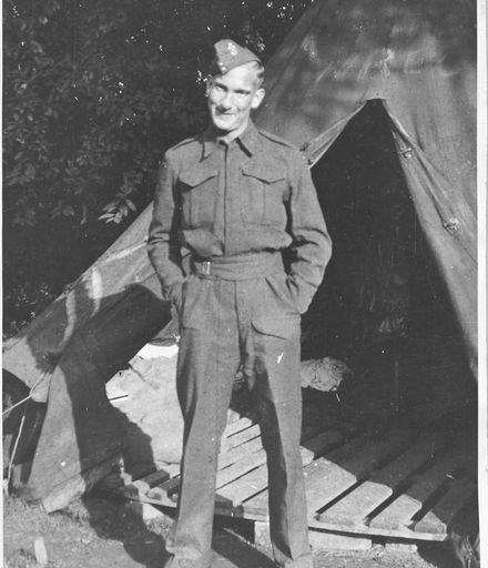 A soldier, probably Jack Kingsbury, standing outside a tent with a wooden pallet floor.