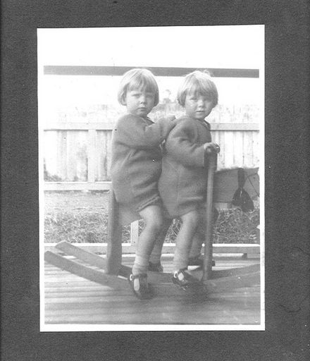 Two unidentified girls on a wooden rocking horse