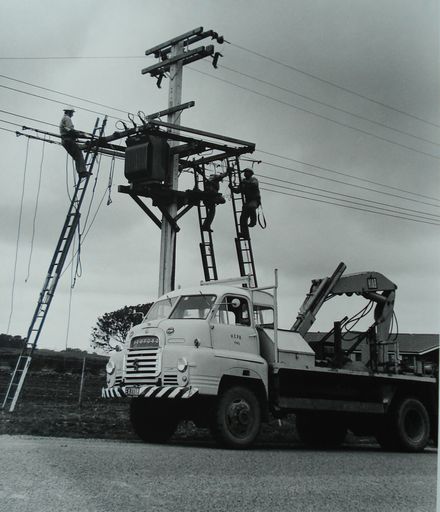 Linemen installing transformer on power pole, rural area