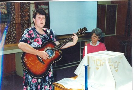 Woman (unidentified) playing guitar at Sunday's 'Church Service' - Resource cover image