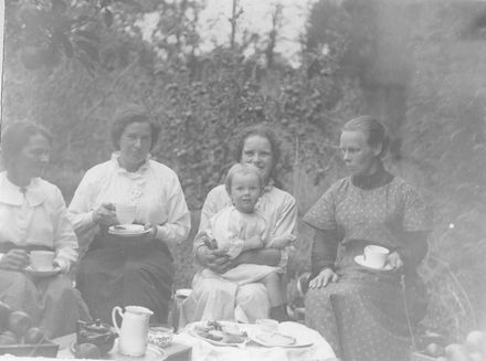 Four women and toddler having morning or afternoon tea in garden