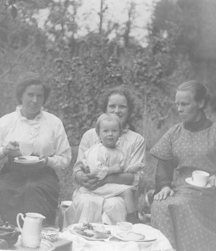 Four women and toddler having morning or afternoon tea in garden