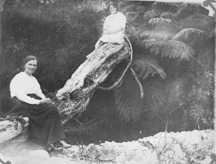 Hebe and Connie Blackburn sitting on log beside stream or river
