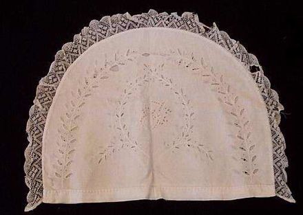 Teapot cosy cover with embroidered arching sprigs.