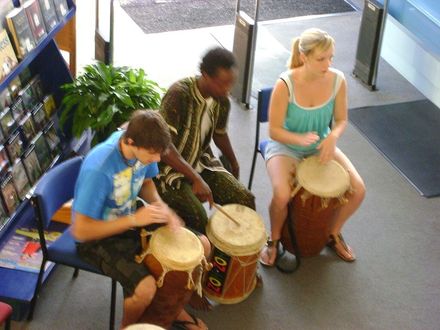 Francois Byamana drumming with 2 participants in Levin Library