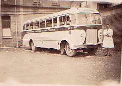 Ken Watts standing beside Ford bus, 1947