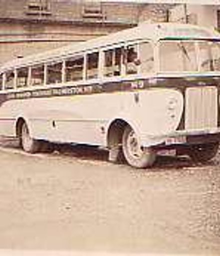 Ken Watts standing beside Ford bus, 1947