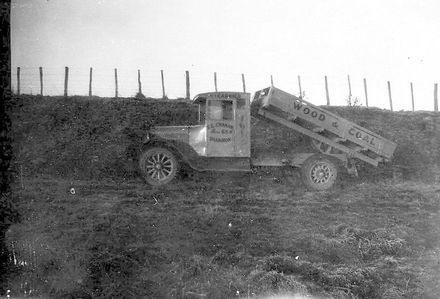 Truck (Wood & Coal signage) in paddock with tray raised for dumping