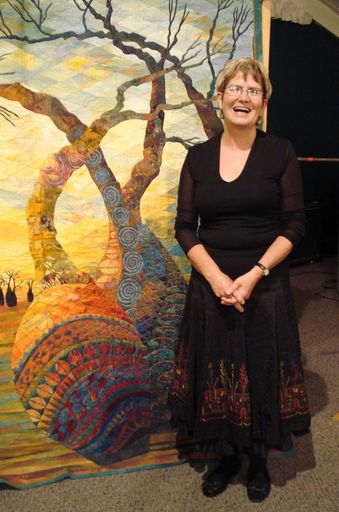 Gloria Loughman standing by quilt