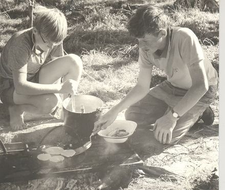 Boys making pikelets on wood fire outdoors