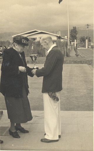 Mrs Lett presnting a bowling cup / trophy to an unidentified man.