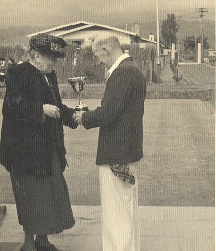 Mrs Lett presnting a bowling cup / trophy to an unidentified man.