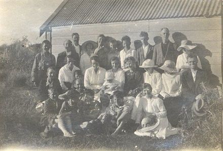 Group of men and women by a shed.