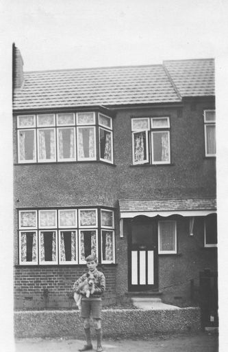 Boy with scotty dog outside 2 story brick house.