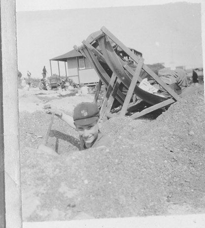 Boy digging large hole at beach.