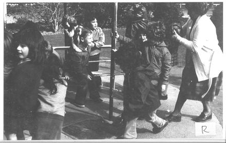 Children grouped together in unidentified playground ?