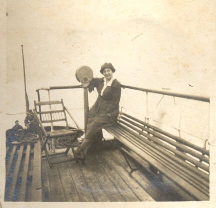 Woman with hat sitting on deck of ship (liner?)